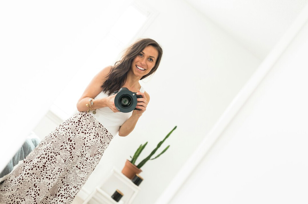 Studio portrait of a woman photographer smiling, holding a camera
