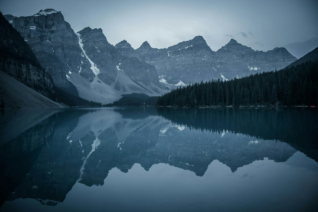 Snow-capped mountain peaks reflected in a still alpine lake in Banff, Canada